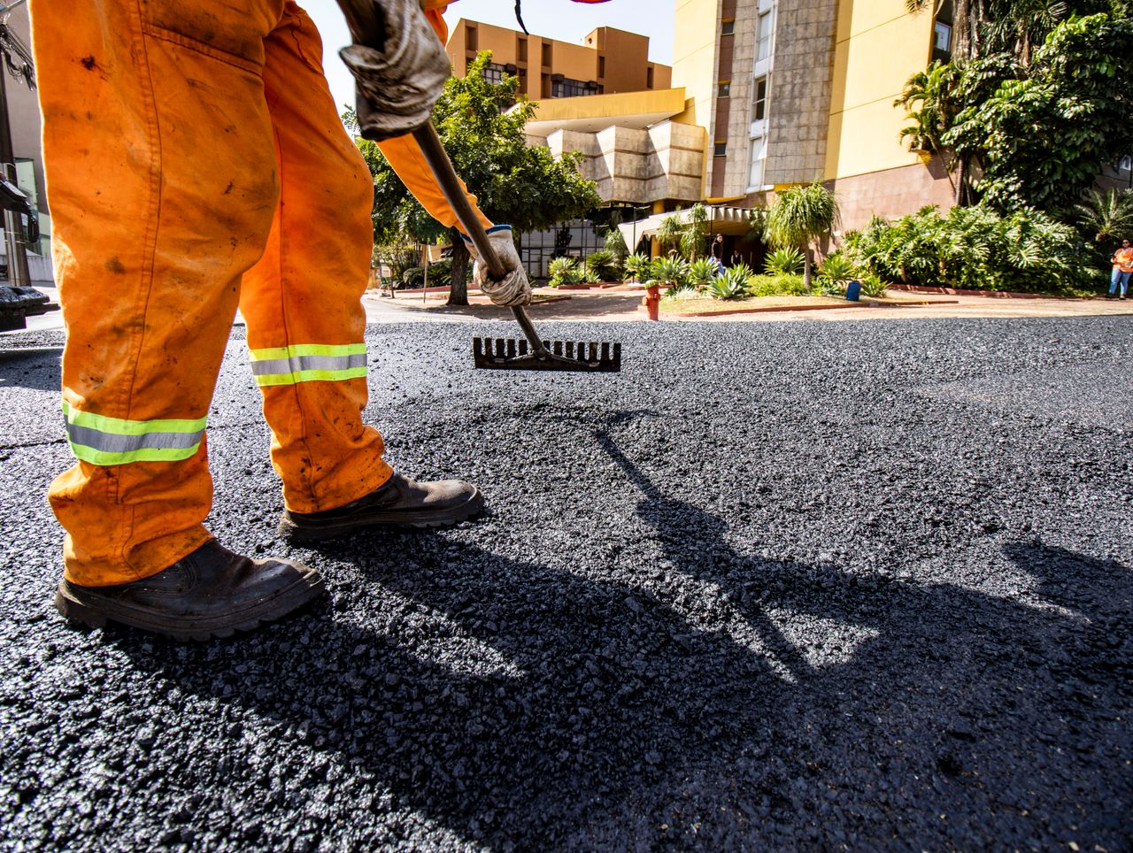Worker in orange gear paving a road in Londrina city during daytime.